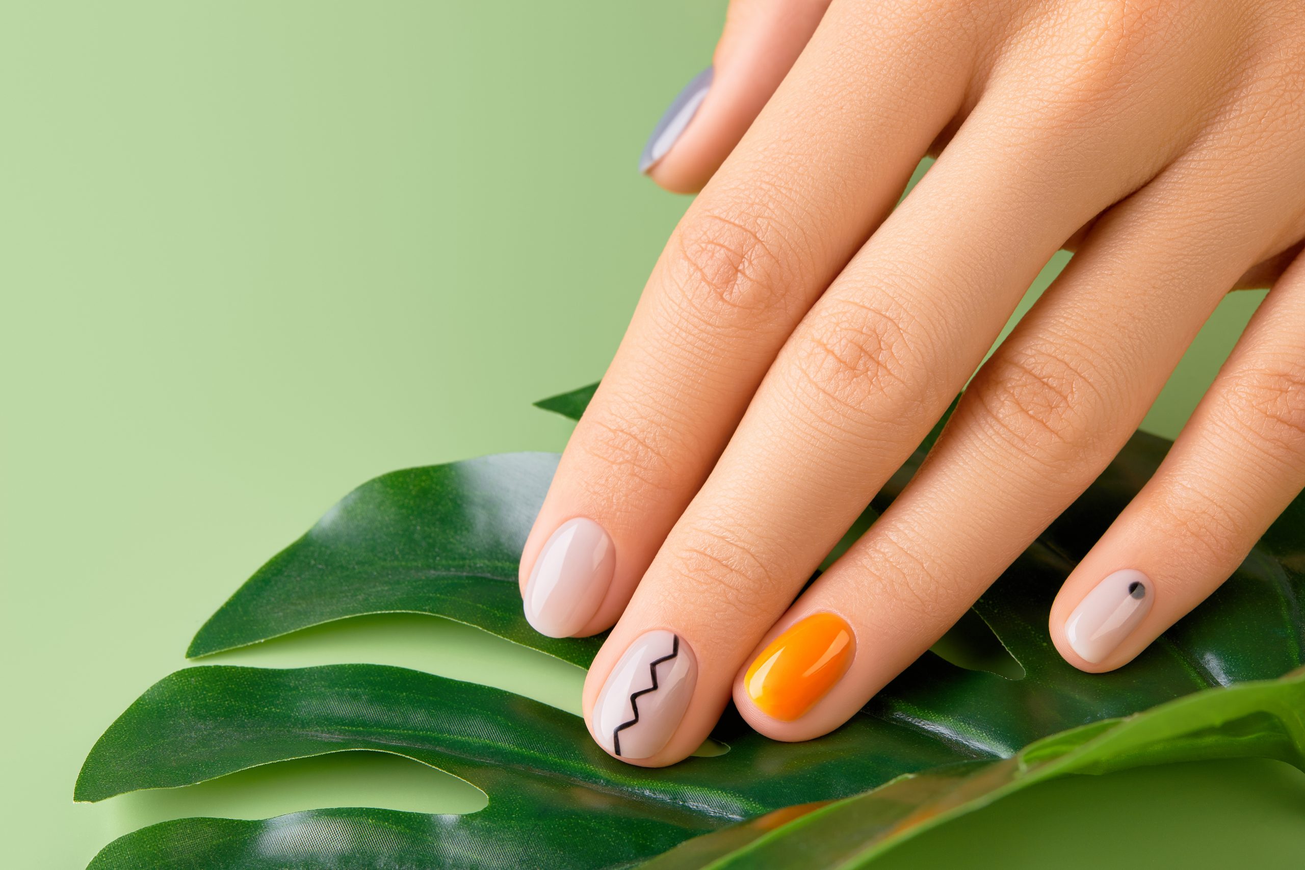 beautiful-womans-hand-with-minimal-nail-design-green-background-manicure-pedicure-beauty-salon-co-scaled