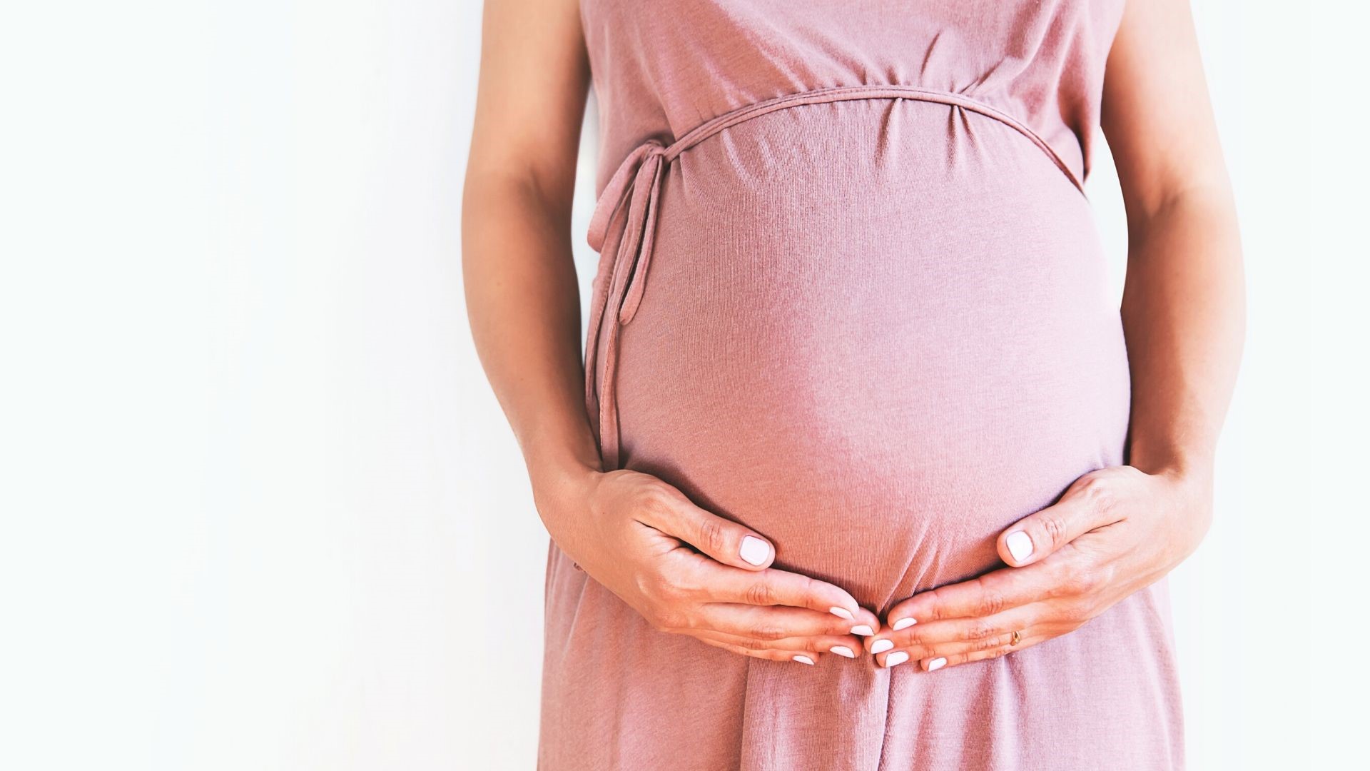 pregnant-woman-wearing-pink-holding-her-belly