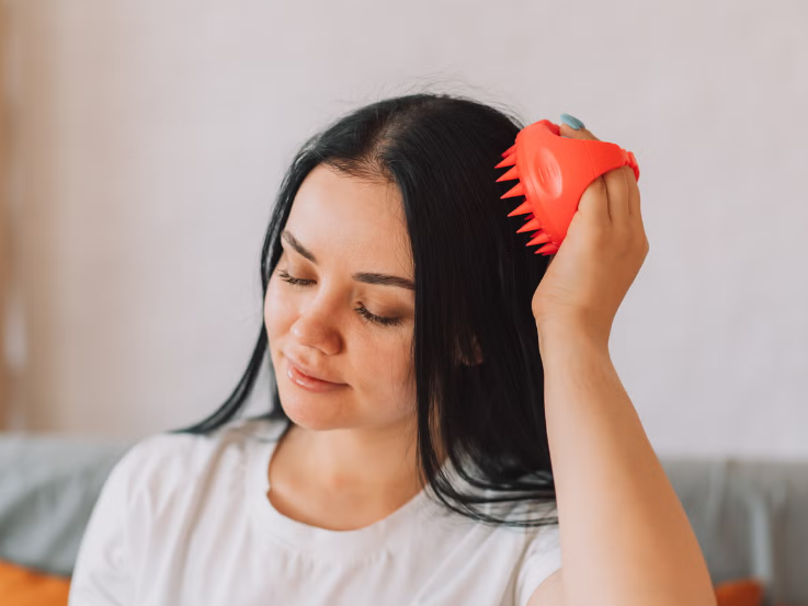 lady_gives_herself_head_massage_with_scalp_massager_royalty_free